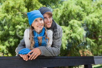 Cute couple standing in the park embracing by a fence