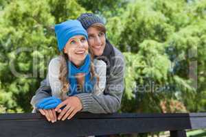 Cute couple standing in the park embracing by a fence