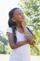 Little girl thinking with arms crossed in the park