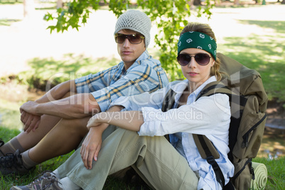 Active couple sitting down on a hike looking at camera