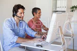 Casual business team working at desk using computers with man us