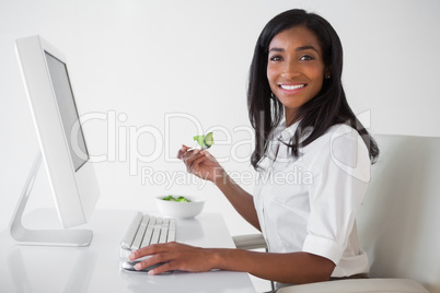 Casual pretty businesswoman eating a salad at her desk