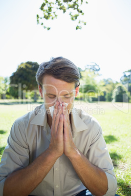 Stylish man blowing his nose in the park