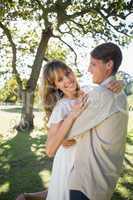 Smiling young couple embracing in park