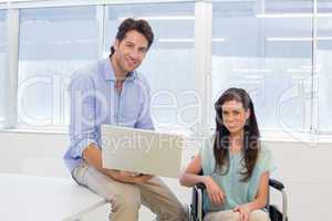 Businessman with laptop and businesswoman in wheelchair
