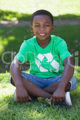 Young boy sitting on grass in recycling tshirt