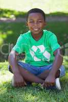 Young boy sitting on grass in recycling tshirt