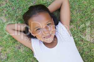 Little girl lying on the grass smiling at camera