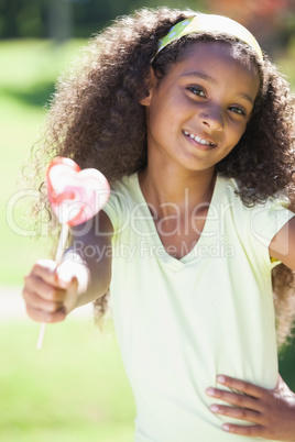 Young girl holding a heart lollipop in the park