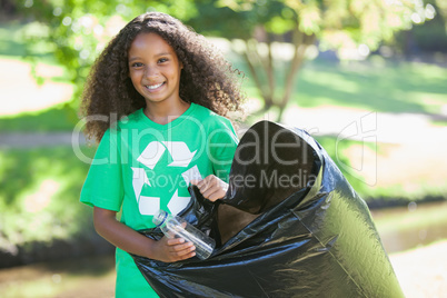 Young environmental activist smiling at the camera picking up tr