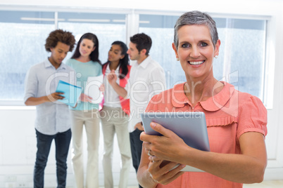 Businesswoman smiles at camera while looking at tablet pc with c