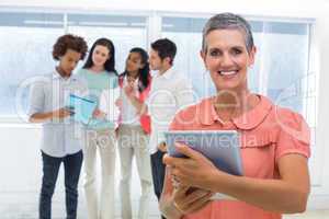 Businesswoman smiles at camera while looking at tablet pc with c