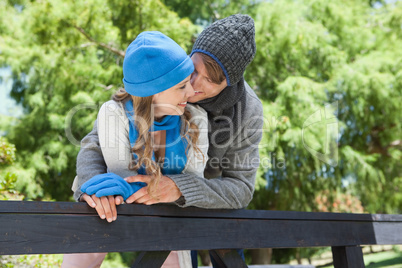 Cute couple standing in the park embracing by a fence
