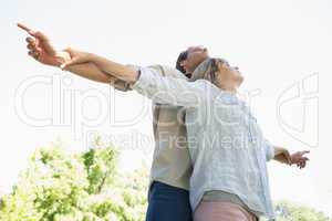 Carefree couple standing with arms out in the park