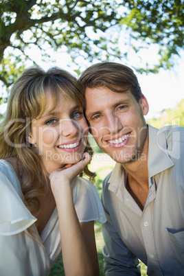 Cute couple sitting outside at a cafe smiling at camera