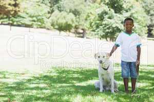 Little boy standing with his pet labrador in the park