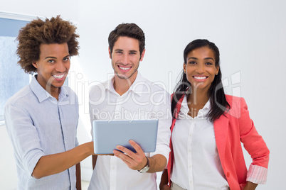 Three colleagues working on tablet pc smile to camera