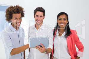 Three colleagues working on tablet pc smile to camera