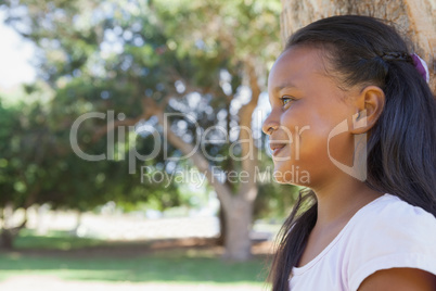 Little girl sitting by tree smiling