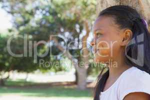 Little girl sitting by tree smiling