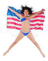 American girl in bikini leaping holding flag