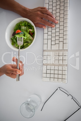 Businesswoman eating a salad at her desk