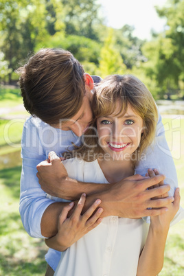Cute couple hugging in the park with girl smiling at camera