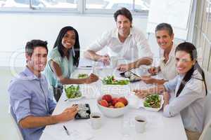 Workers smile at camera while eating healthy lunch