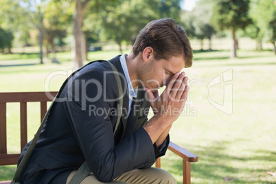 Worried businessman sitting on park bench