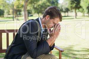 Worried businessman sitting on park bench