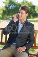 Casual businessman talking on phone on park bench