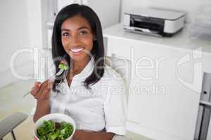 Casual pretty businesswoman eating a salad at her desk