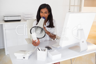 Angry businesswoman shouting in megaphone at phone