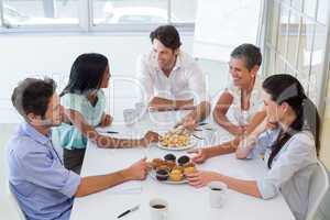 Business people chat while eating muffins and drinking coffee