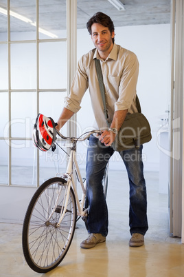 Casual businessman pushing his bike smiling at camera Casual businessman pushing his bike smiling at camera