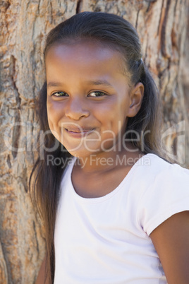 Little girl by large tree smiling at camera