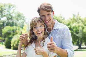 Attractive couple smiling at camera and showing thumbs up in the