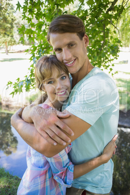 Close young couple standing together in the park smiling at came Close young couple standing together in the park smiling at came