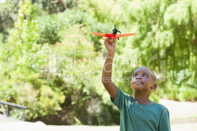 Happy little boy flying toy airplane