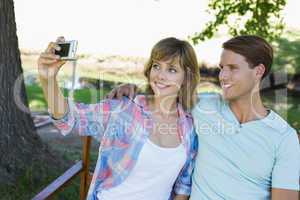 Cute couple sitting on bench in the park taking a selfie