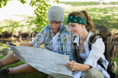 Active couple sitting down on a hike reading map