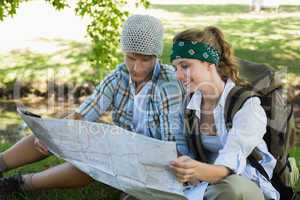 Active couple sitting down on a hike reading map