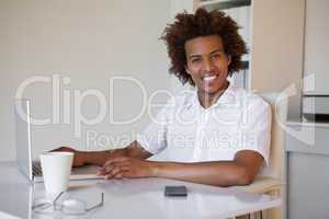 Casual businessman smiling at camera at his desk