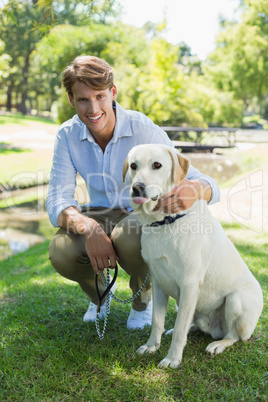 Handsome man with his labrador in the park smiling at camera