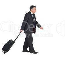 Mature businessman pulling his suitcase