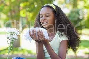 Young girl sitting by flower and sneezing in the park