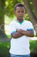 Little boy frowning at camera with arms crossed in the park