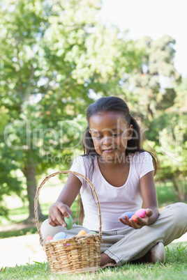 Little girl sitting on grass counting easter eggs