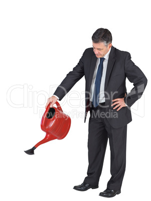 Mature businessman watering with red can