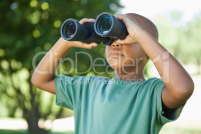 Little boy looking up through binoculars in the park